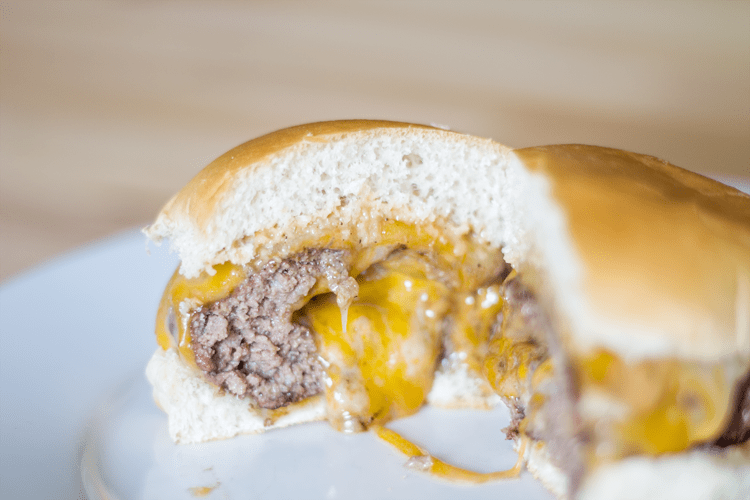 Cheese oozing from the inside of a cheeseburger