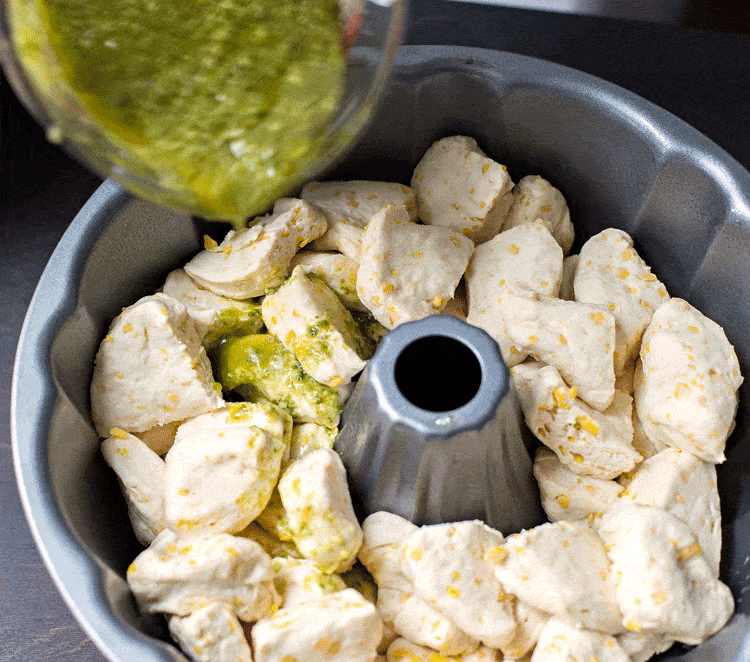 Drizzling pesto garlic butter sauce on the biscuit chunks Drizzling pesto garlic butter sauce on the biscuit chunks