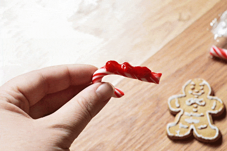 Placing red frosting on the mini candy cane Placing red frosting on the mini candy cane