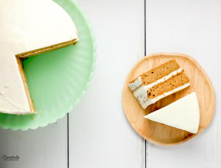 Perfect spring cake - Carrot Spice Cake made with Greek yogurt and frosted with a cream cheese frosting. 2 slices of carrot cake and a green cake stand.