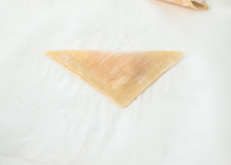 Apple Pie Wontons with cinnamon sugar and powdered sugar Folding over wonton wrapper
