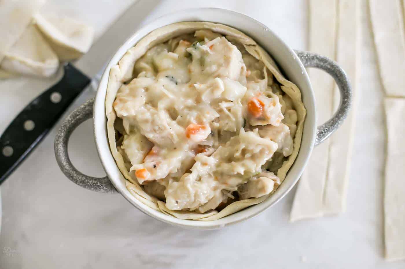 Placing the chicken pot pie filling into the base of the puff pastry in the soup bowl. Placing the chicken pot pie filling into the base of the puff pastry in the soup bowl.