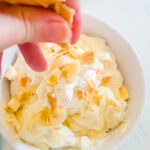 adding crumbled waffle cookies to the top of banana pie dip