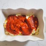 adding pizza sauce to top of cheese mixture